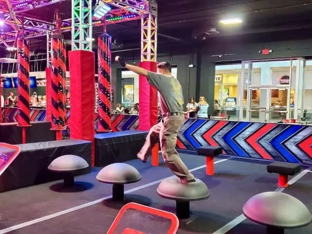 a man leaping between obstacles in a ninja warrior course